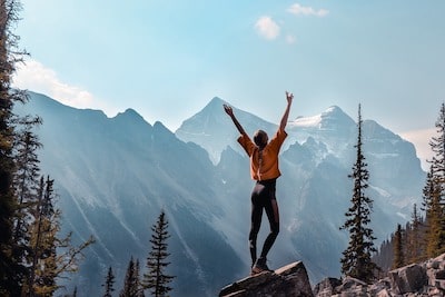 woman on hilltop with hands up looking joyful