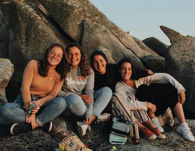 group of teen girls sitting on rocks smiling